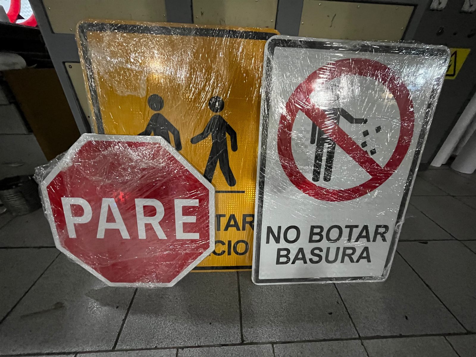 Señales viales Pare, cruce peatonal y No Botar Basura recién fabricadas en el taller
